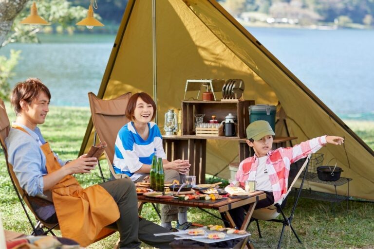 Asian family camping outdoors with a tent and table full of food