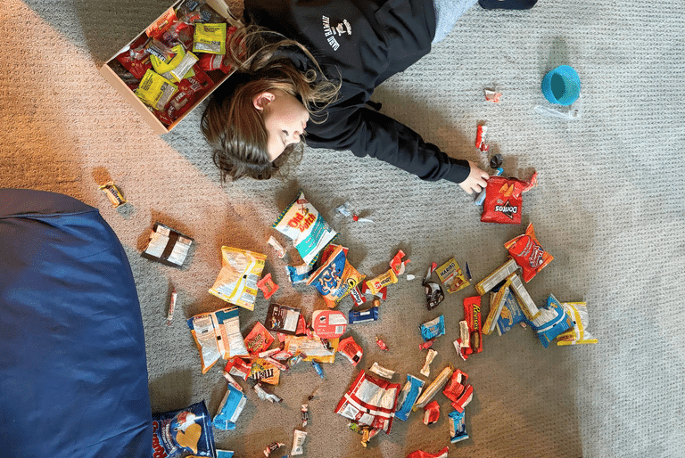 how to handle all the Halloween candy - a girl surrounding by candy on the floor