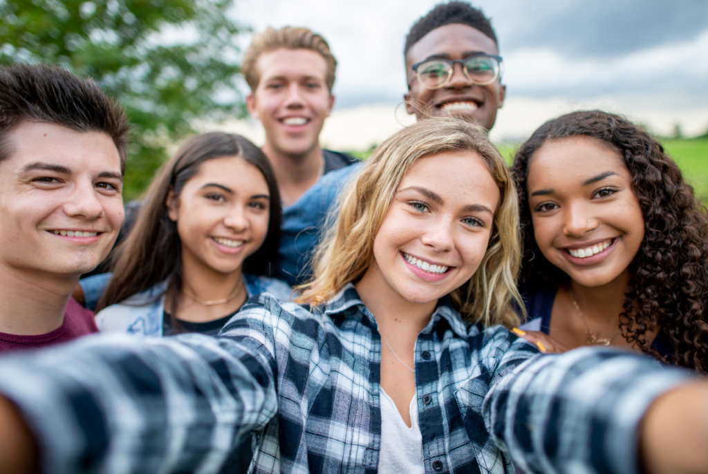 a bunch of teens taking a selfie together while smiling outdoors