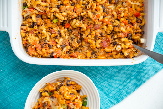 top down view of mac and cheese in a casserole dish with lots of mix ins such as black beans and tomatoes