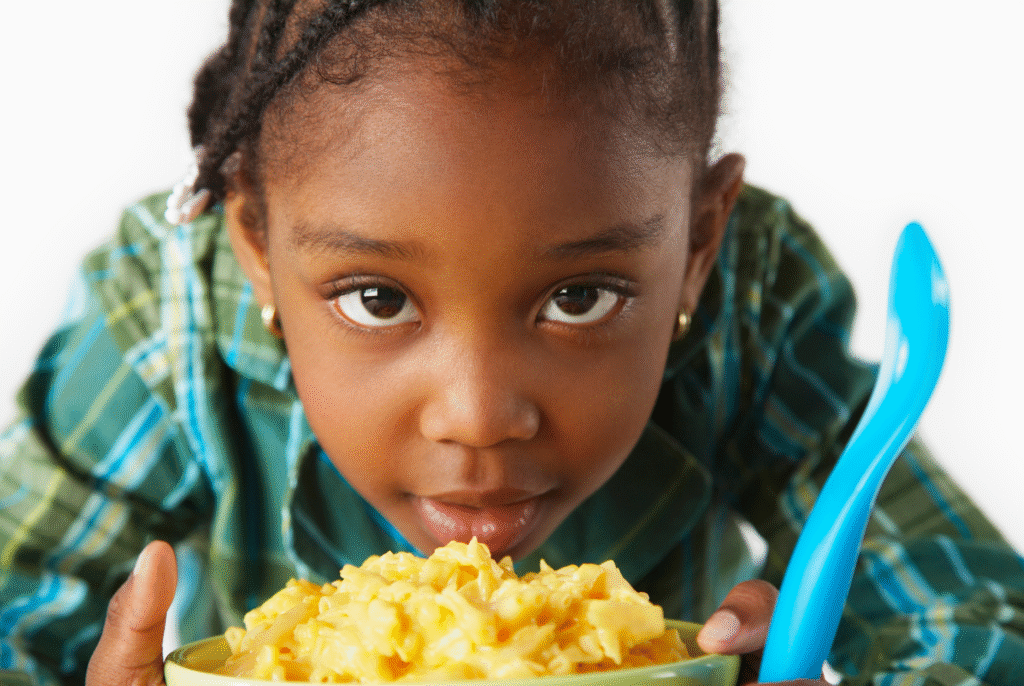 close up of a little girl with a big bowl of mac and cheese