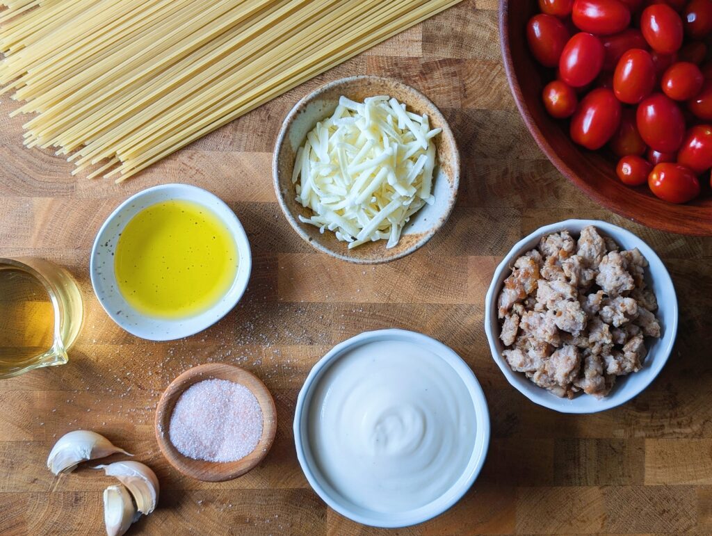 top down ingredients needed for skillet pasta including pasta, meat, tomatoes