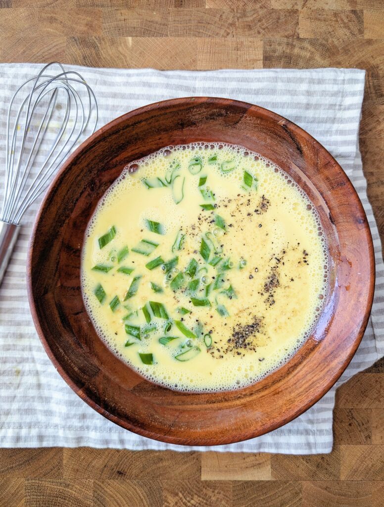 In a medium bowl, whisk together eggs and milk. Stir in garlic powder, salt, pepper, and optional herbs.