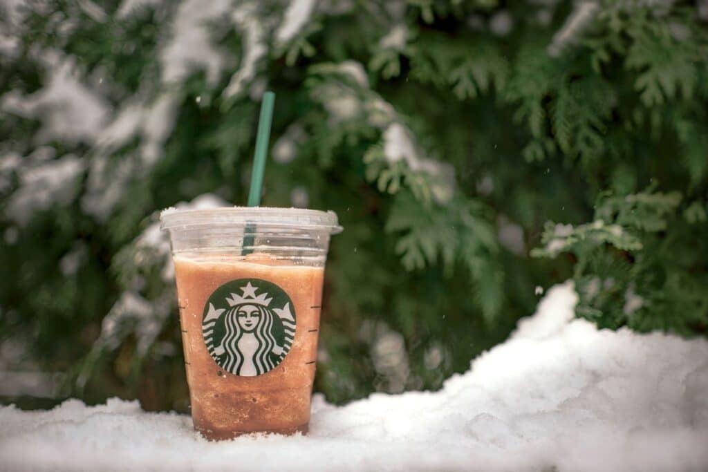 holiday starbucks drink on a snowy backdrop with evergreens
