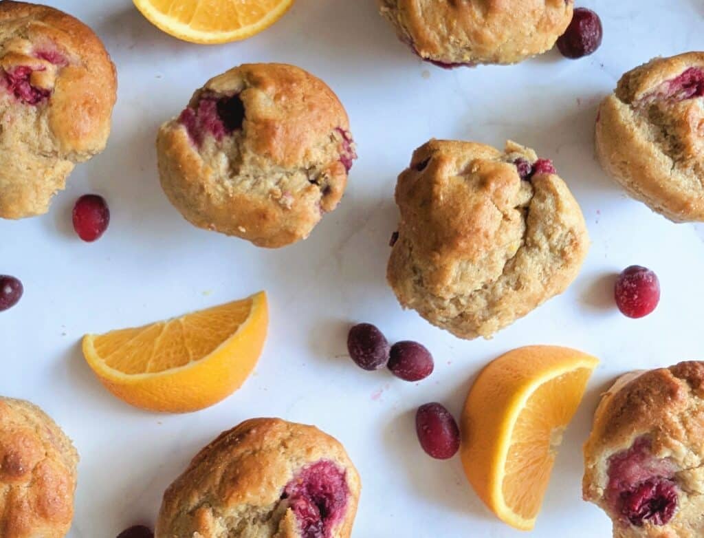cranberry orange protein muffins on a table with cranberries