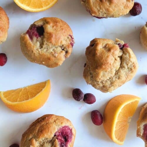 cranberry orange protein muffins on a table with cranberries