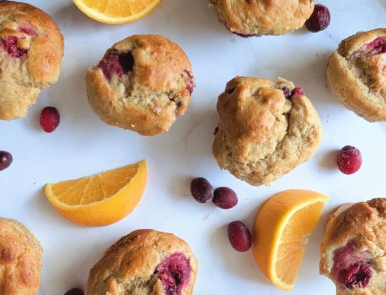 cranberry orange protein muffins on a table with cranberries