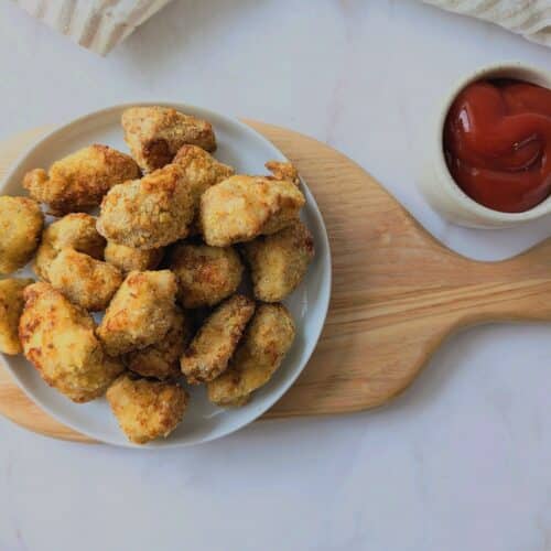 crispy air fryer chicken nuggets on a wooden board with ketchup