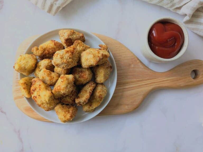 crispy air fryer chicken nuggets on a wooden board with ketchup