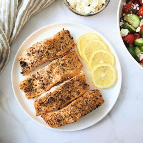 air fryer Greek salmon on a plate with a side of Greek salad