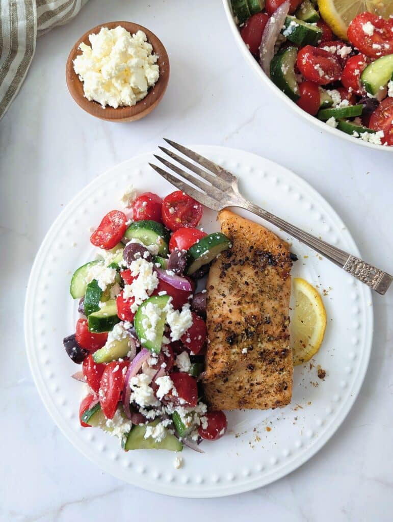 top down view of air fryer Greek salmon wedge on a plate with a side of salad