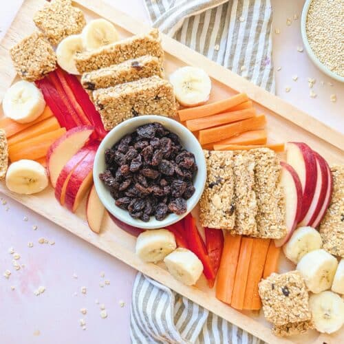 no-bake peanut butter oat bars on a wooden platter with cut fruit