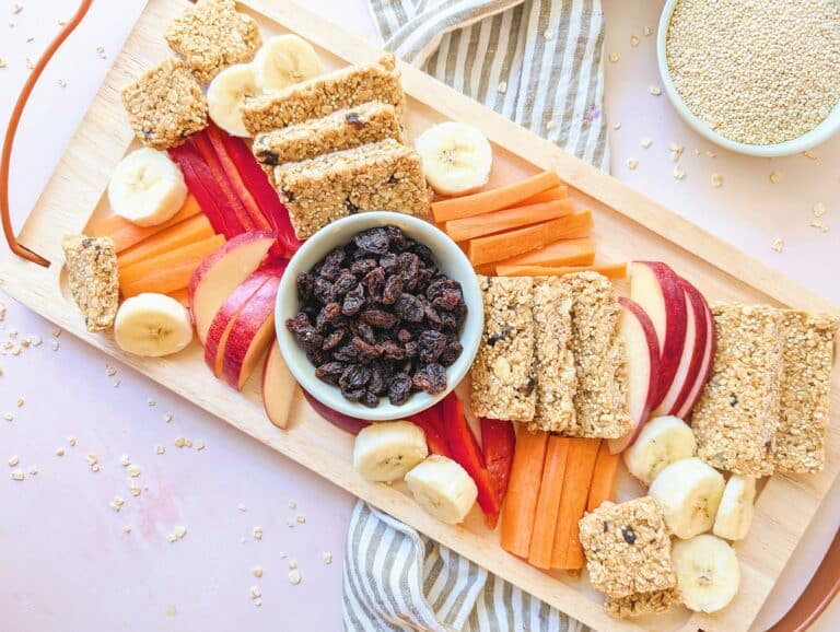 no-bake peanut butter oat bars on a wooden platter with cut fruit