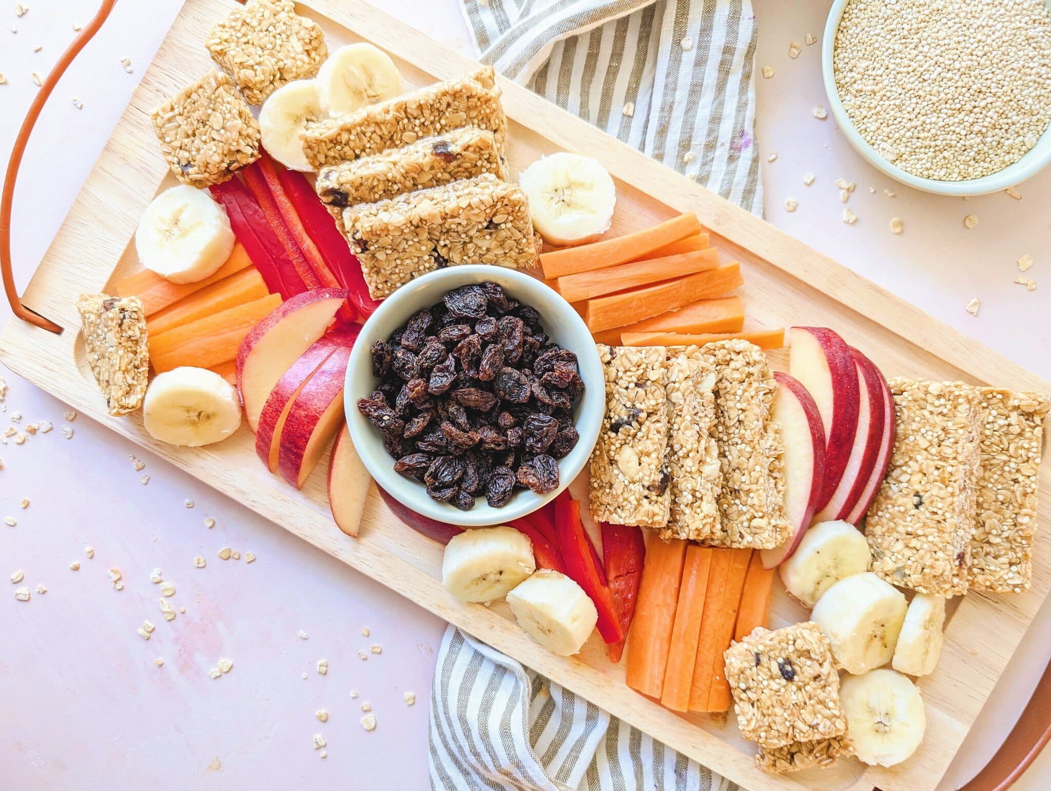 no-bake peanut butter oat bars on a wooden platter with cut fruit
