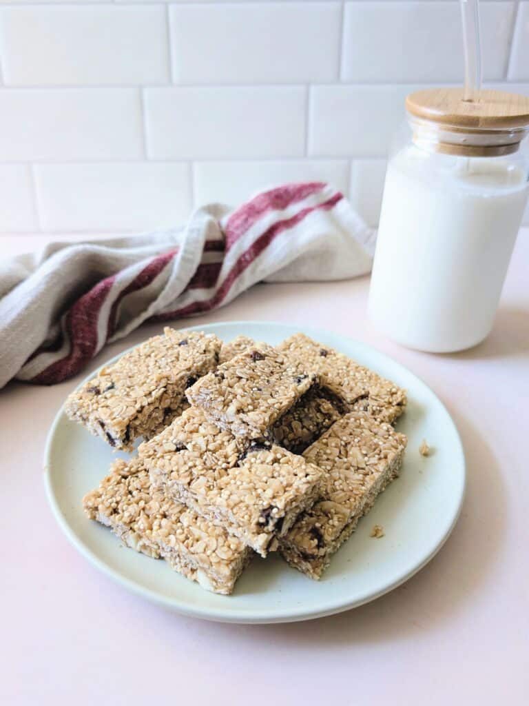 side view of peanut butter oat bars with quinoa and a glass of milk on the side