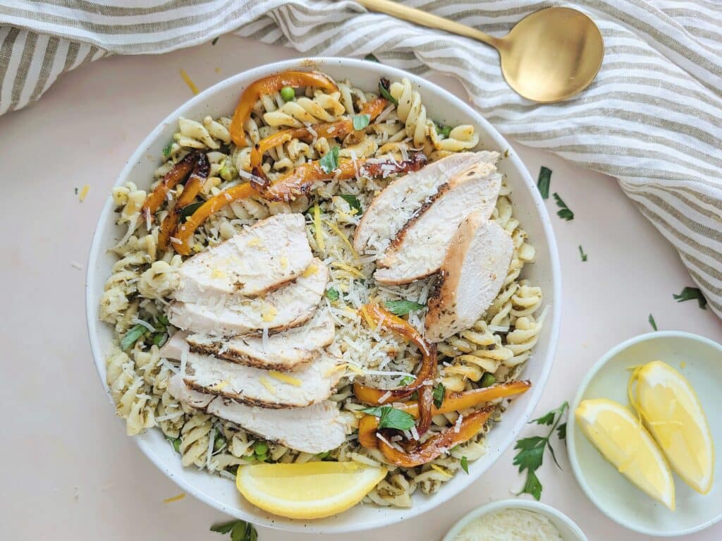 big bowl of chicken pesto pasta with lemon slices