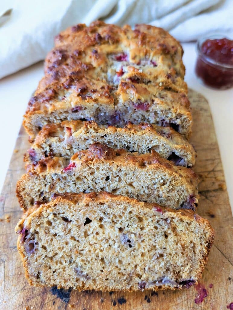 side view of strawberry snacking loaf in slices on a wooden cutting board