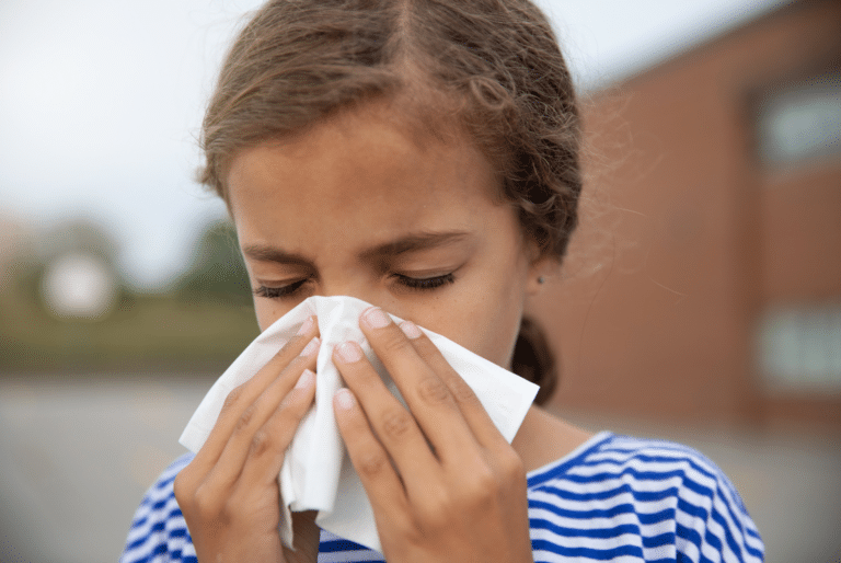 close up of a girl at school blowing her nose. She should have eaten foods to support her immune system