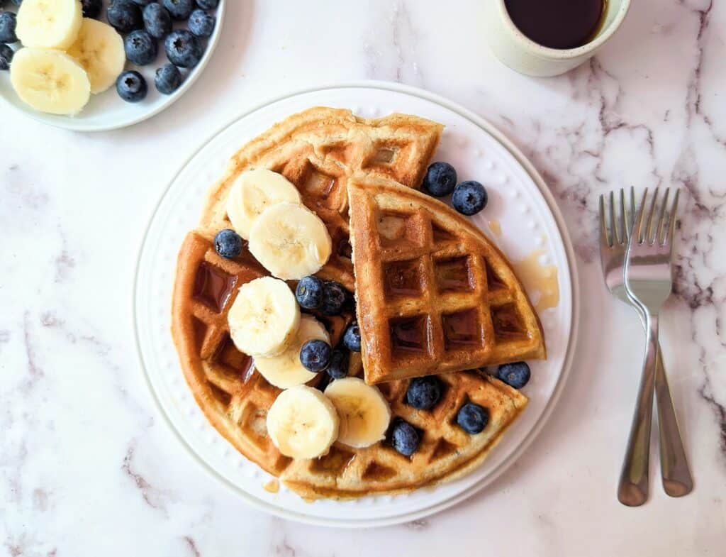 protein waffles for kids on a plate with syrup bananas and berries